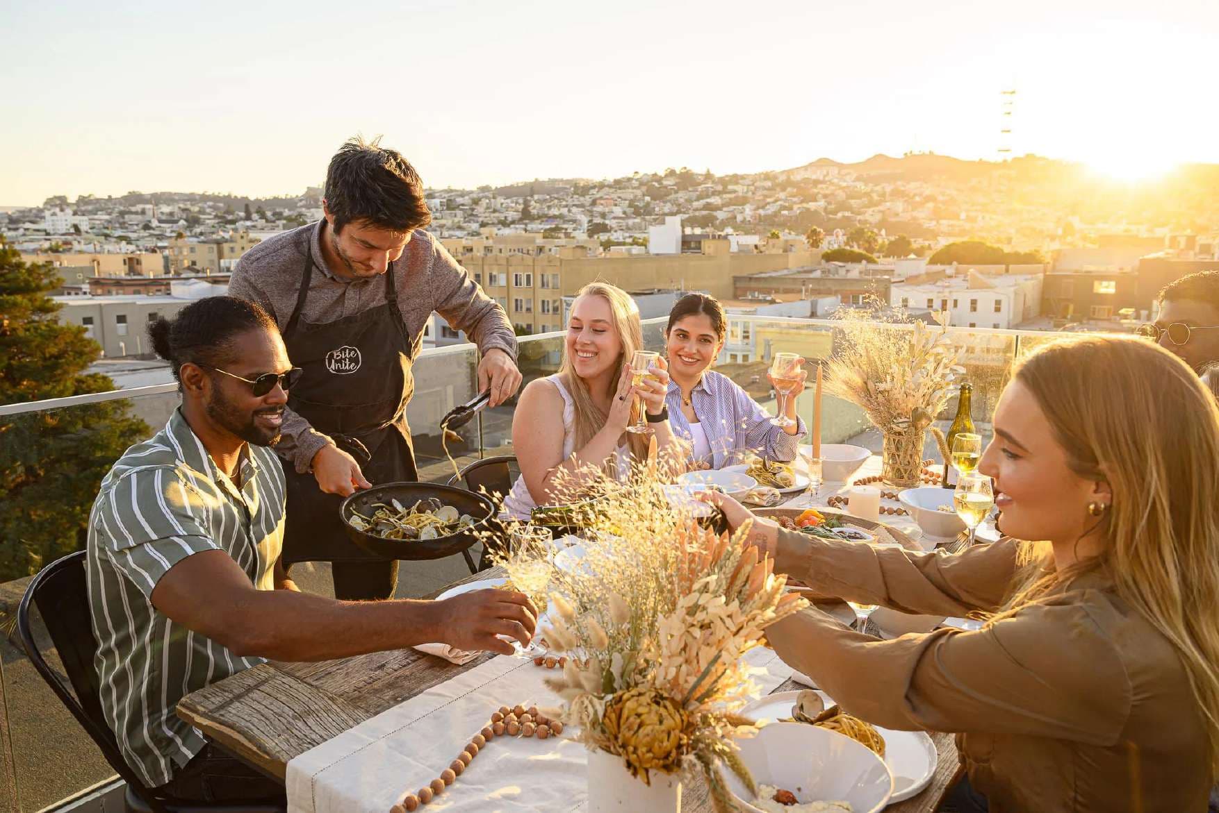 Friends sharing dinner on a rooftop at golden hour