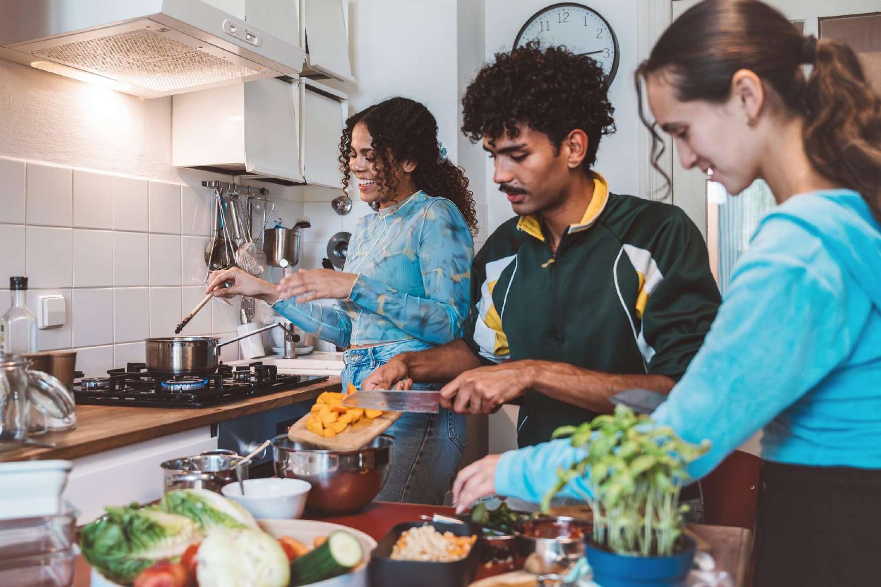 Housemates cooking together in a small bright kitchen