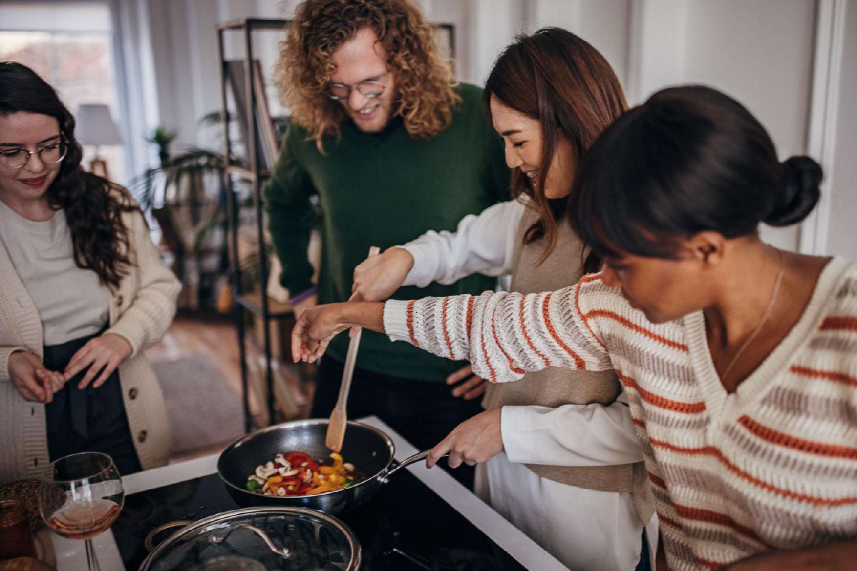 Friends cooking vegetables in a pan together