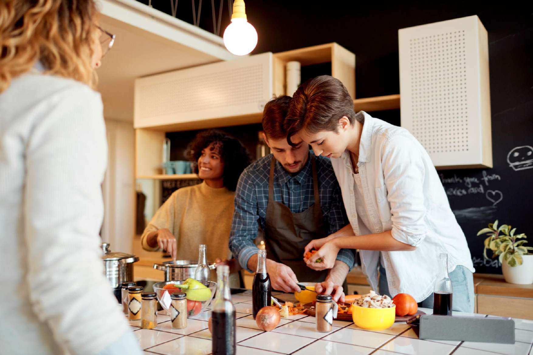 Housemates preparing dinner in a chalkboard kitchen
